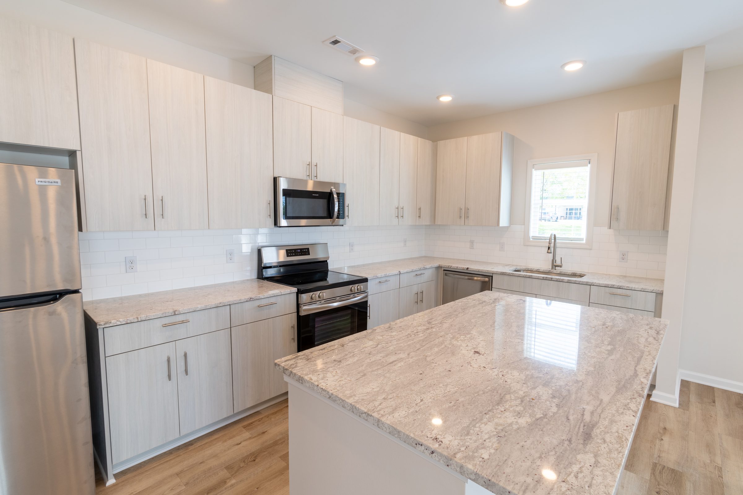 Kitchen with white cabinets, stainless refrigerator, and island